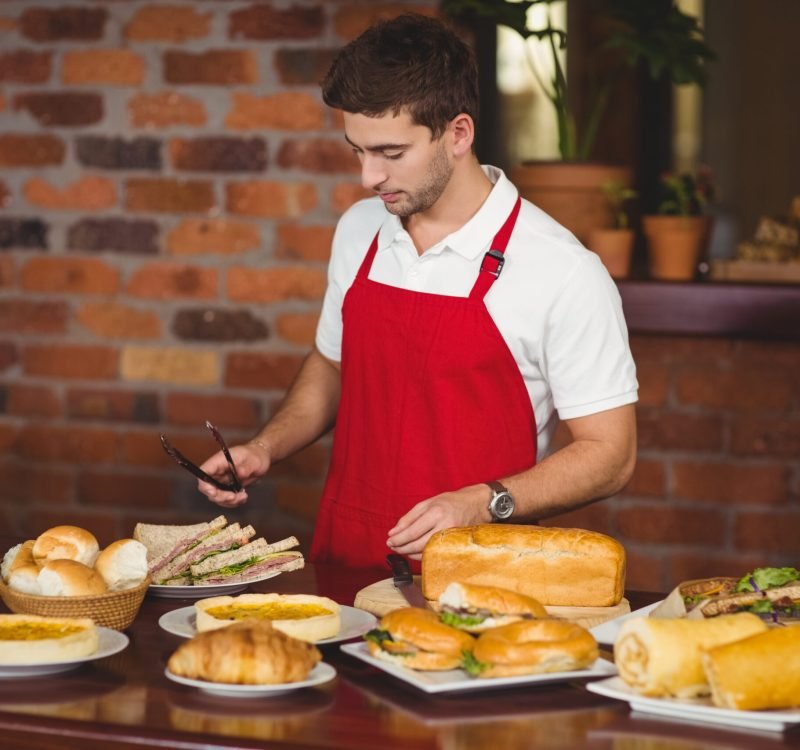 Handsome waiter about to pick a roll at the coffee shop